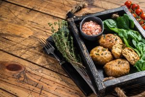 Seafood Fish balls or Fish cake with spinach and herbs in a tray. Wooden background.